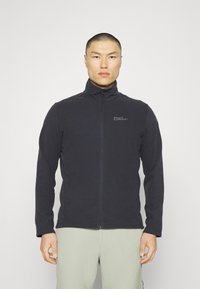 Schwarze Fleecejacke mit hohem Kragen, vollem Reißverschluss und Logo auf der Brust. Verfügt über eine glatte Textur und einen figurbetonten Schnitt.