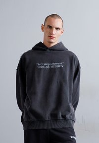 Grauer, übergroßer Hoodie mit Frontdruck: "Art Department" 1995-08 MISBHV, aus weichem, strukturiertem Baumwollstoff, mit verstellbarem Kapuzenzug.