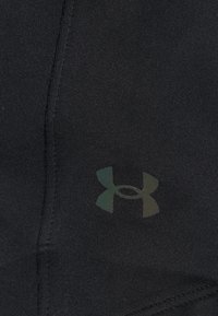 Schwarzer Stoff mit einem kleinen, dezenten Under Armour-Logo, das nahe einer Naht in der Mitte des Materials aufgedruckt ist.