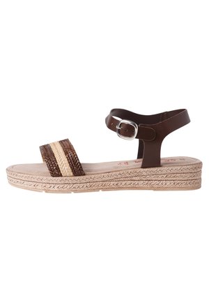 Braune Leder-Sandale mit geflochtenen Akzenten, beigem Plateau-Sohl, verstellbarem Knöchelriemen und strukturierten Details auf dem Fußbett.