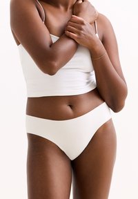Witte katoenen ondergoed in een gladde, minimale stijl met een brede elastische tailleband, gecombineerd met een witte tanktop.
