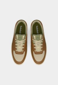 Καφέ και μπεζ αθλητικά παπούτσια με επάνω μέρος από δέρμα και ύφασμα, στρογγυλεμένη μύτη, δέσιμο με κορδόνια και πράσινες λεπτομέρειες στο πάτο και το λογότυπο.