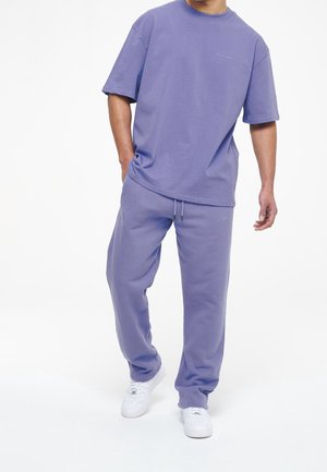 Paarse katoenen t-shirt met korte mouwen en een ontspannen pasvorm, gecombineerd met bijpassende paarse trainingsbroek. Beschikt over een trekkoord in de taille en logo-detail.