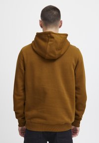 Hoodie en polaire marron avec une capuche à cordon de serrage, des poignets et un ourlet côtelés. Texture douce, design minimaliste, sans logos ni graphiques visibles.