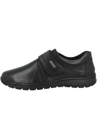 Schwarze Lederschuhe mit glatter Oberfläche, einem Klettverschluss, gepolstertem Schaft und flexibler Gummisohle.