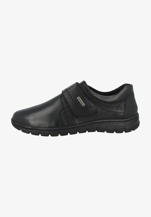 Schwarze Lederschuhe mit glatter Oberfläche, einem Klettverschluss, gepolstertem Schaft und flexibler Gummisohle.
