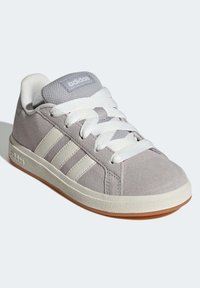 Šedé semišové tenisky s bílými tkaničkami, třemi bílými pruhy po straně a krémovou gumovou podrážkou. Na jazyku mají vyražené logo.