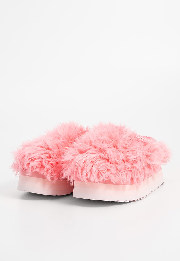 Rosa, flauschige Hausschuhe mit einer dicken, weichen Textur und einer Plattformsohle. Das Design zeigt ein flauschiges Material, das das Oberteil bedeckt. Horizontale Streifen auf der Sohle.