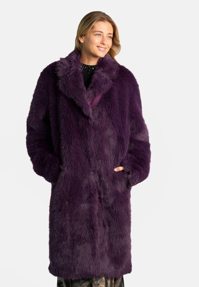 Abrigo de piel sintética morado con un gran cuello de solapa, mangas largas y bolsillos frontales. Textura suave y corte holgado y oversized.
