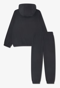 Tume värvi kerge sportülikond, mis koosneb kapuutsiga jupist ja elastse vöökohaga pükstest, millel on äärtel mansetid ning sile pind.