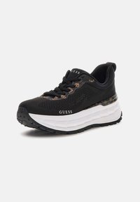 Sneaker sportivo nero con tomaia in rete, suola intermedia spessa bianca, suola esterna in gomma nera e motivo decorativo sul lato. Logo sulla linguetta.