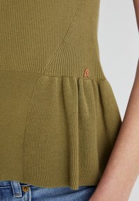 Olivroheline ribaga kootud tops, millel on laienev peplum alläär ja väikene vaskhalline tikandlogoga alumises osas.
