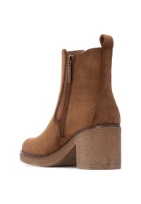Stivale alla caviglia in suede marrone con cerniera laterale, punta arrotondata e tacco spesso e testurizzato. Dotato di un gancio per una facile calzata.