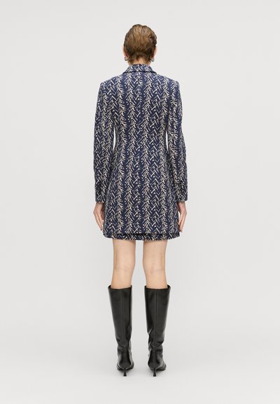 Rochie cu model marin, cu mâneci lungi și croială ajustată. Prezintă un design abstract de culoare deschisă. O pereche de cizme negre până la genunchi.