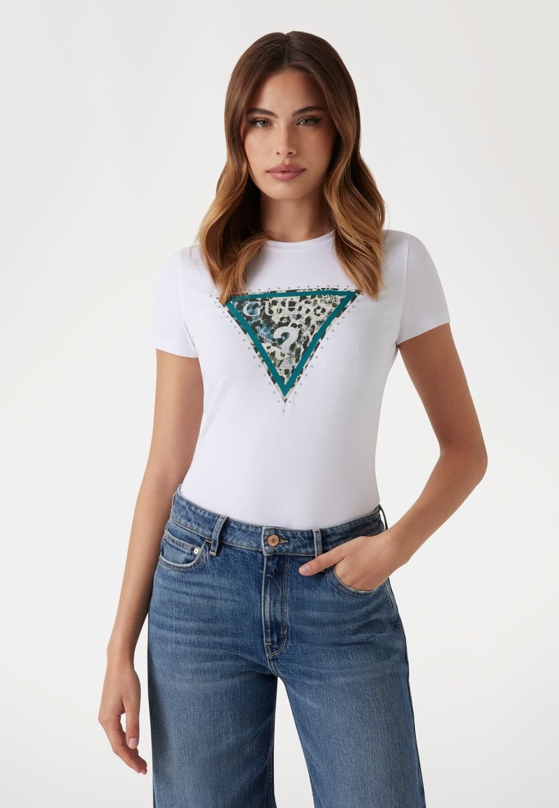 Hvid tætsiddende T-shirt med et trekantet grønt og leopardprint design. Har glitrende dekorationer omkring grafikken. Matchet med blå jeans.
