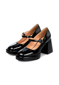 Zwarte gepatineerde leren Mary Jane schoenen met een brede strap, cirkelvormige gespaccent, ronde neus en chunky vierkante hak. Soepele textuur.