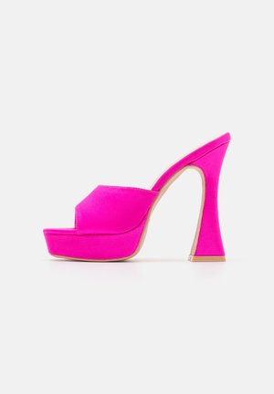 Mule de tacón alto de color rosa brillante con puntera abierta, amplia tira frontal, suela con plataforma y tacón bloque acampanado sobre fondo blanco.