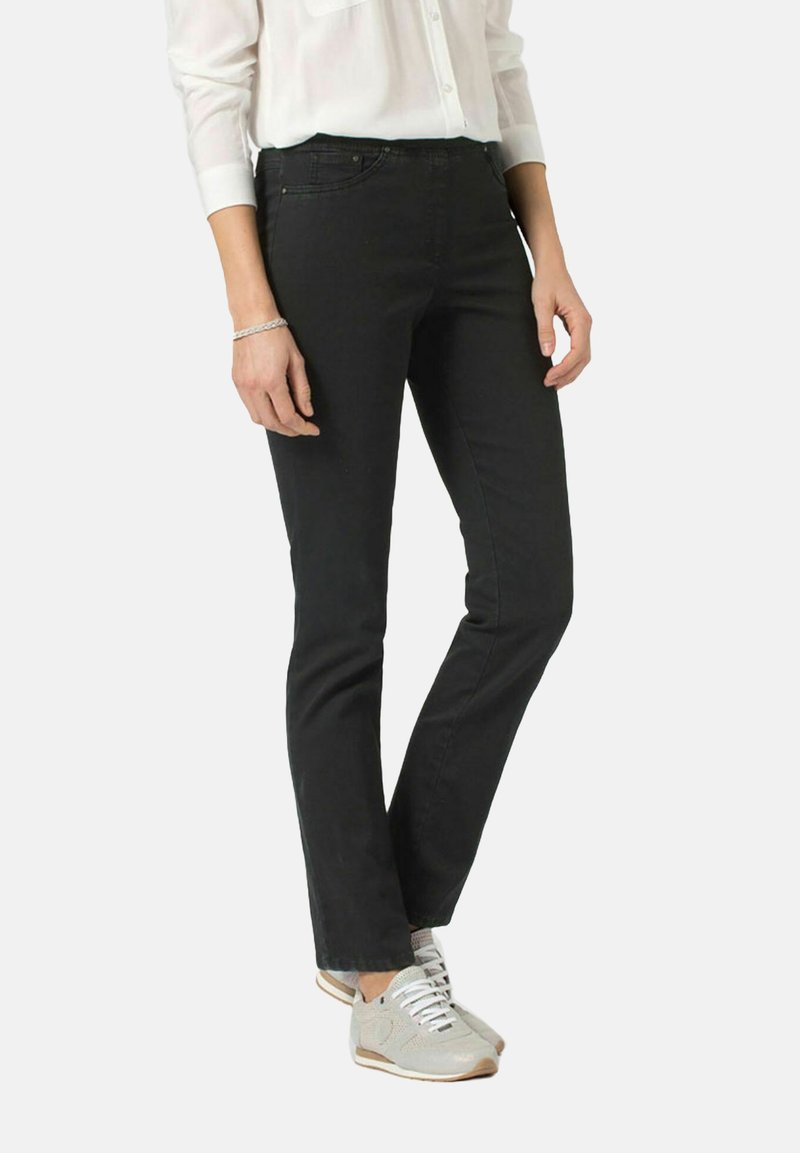 Czarne dżinsy o slim fit, pięć kieszeni oraz minimalne detale przeszyć. Noszone z białą koszulą i szarymi trampkami.