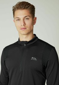 Schwarzes Zip-Up-Oberteil mit langen Ärmeln, das ein geometrisches Berglogo, einen strukturierten Stoff und kontrastierende Schulterpaneele aufweist.