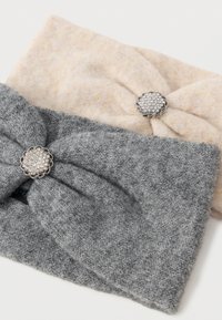 Duas faixas de cabelo feitas de tecido de malha suave. Uma é bege claro com um design de nó, e a outra é cinza escuro, ambas com detalhes decorativos em prata.