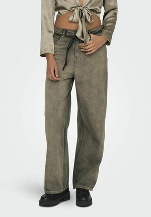 Lanneleveit i falmet olivengrønn denim, med en snor i livet og en avslappet passform. Kombinert med en kort satin topp og svarte sko.