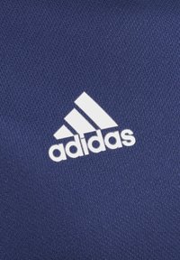 Tmavě modrá látka s bílým logem značky Adidas. Textura je hladká s mírným elastickým efektem a logo je výrazně zobrazeno.