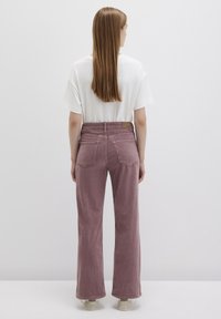 Lavender corduroy wide-leg pants with back pockets, attached label, and textured fabric. Paired with a plain white t-shirt.