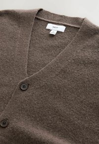 Brown cardigan made from soft knitted fabric, featuring a V-neck design, two front buttons, and a label with "NEXT" inside.