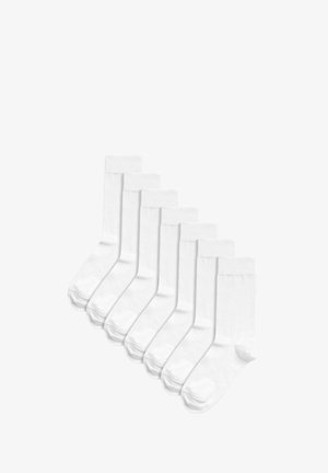 Białe bawełniane skarpetki typu crew, z prążkowanym ściągaczem, wzmocnionym piętą i gładką fakturą, ułożone w rzędzie. Zestaw siedmiu par.