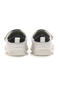 Weiße Lederschuhe mit runder Form, ausgestattet mit einem schwarzen Innenfutter und grauen Akzenten. Enthält eine Schlaufe an der Rückseite für einfaches Anziehen.