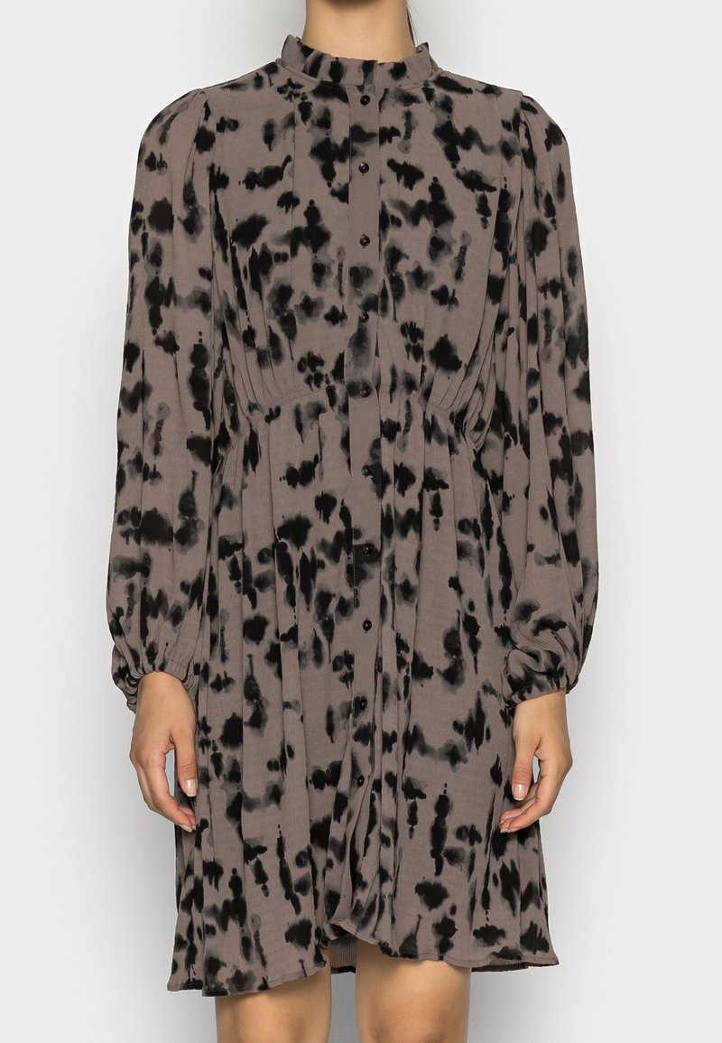 Brown and black spotted dress with high neckline, long puff sleeves, buttons down the front, and gathered waist detail. Soft, textured fabric.