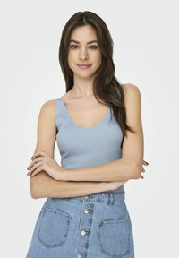 Lichtblauw geribbeld tanktop met een V-hals ontwerp, gecombineerd met een knoopsluiting denimrok met voorzakken en een lichte wassfinish.