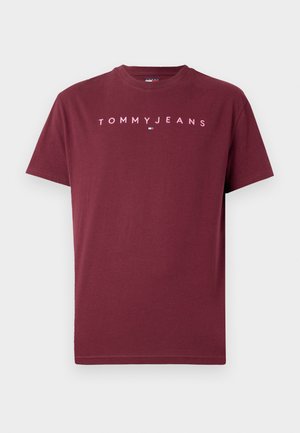 Camiseta de algodón burdeos con cuello redondo, mangas cortas y "TOMMY JEANS" impreso en rosa en el pecho. Textura suave, diseño sencillo.