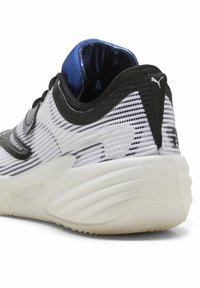 Chaussure de sport noir et blanc avec une tige en mesh, un col rembourré bleu et une semelle texturée. Présente un détail de logo et un design épuré.