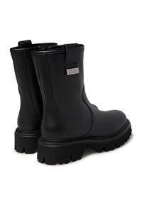 Stivaletti neri in pelle con finitura liscia, suola in gomma robusta e dettaglio del logo su una placca metallica sul retro. Chiusura con cerniera visibile.