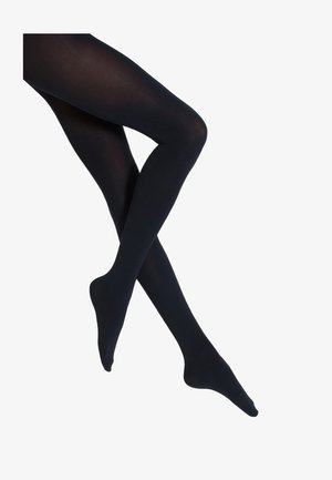 Kryssede ben iført ugjennomsiktige svarte strømper mot en hvit bakgrunn, som klart viser fot- og leggdekning.