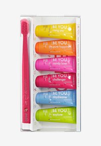 Ensemble de six tubes de dentifrice colorés avec des saveurs distinctes dans des nuances de rose, orange, jaune, bleu, vert et violet ; comprend une brosse à dents rose.