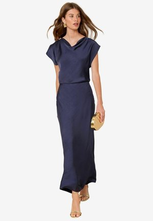 Laivastonsininen satiininen maksimekko, jossa on roikkuva kaula-aukko ja lyhyet hihat. Mekko tarjoaa rennon siluetin ja sileän tekstuurin. Mukana on kultainen clutch-bag.
