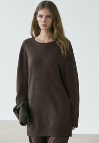 Brązowy, oversize'owy sweter z miękkiego dzianinowego materiału, z okrągłym dekoltem, opuszczonymi ramionami, prążkowanymi mankietami i wydłużonym dołem.