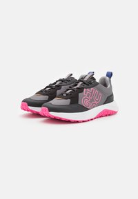Scarpe sportive nere e grigie con accenti rosa, dotate di una suola ammortizzata, tomaia testurizzata e logo del marchio sul lato.