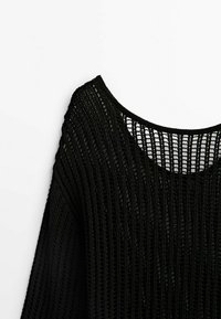 Zwarte gebreide trui met een brede halslijn. Heeft een losse, open geweven textuur en lange mouwen.