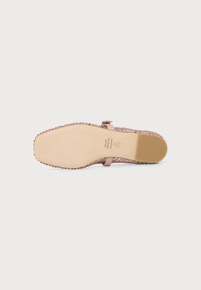 Chaussure plate rose pour femmes avec semelle texturée et bride à la cheville, vue par dessous sur un fond clair uni.