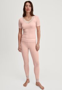 Top ribbed rosa chiaro con maniche corte e scollatura in pizzo, abbinato a leggings ribbed coordinati con dettagli in pizzo alle caviglie.