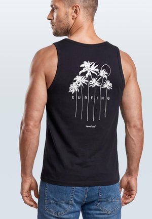 Man wearing black tank top with white palm tree and "SURFING" text design on the back, paired with blue jeans.