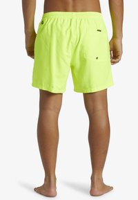 Bañadores de color amarillo neón con cinturilla elástica, bolsillo trasero y una tela suave y ligera. Diseñados para brindar comodidad y movilidad.