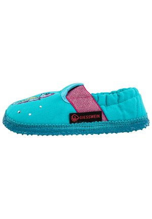 Chausson en tissu turquoise avec bande élastique rose, semelle texturée et accents décoratifs. Présente un design coloré et une étiquette de logo.