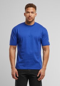Blå crew neck t-shirt lavet af glat stof, med korte ærmer og en let afslappet pasform. Diskret logo-detalje på ærmet.