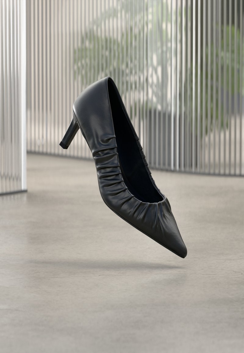 Mustast nahast kõrge kontsaga king, millel on terav nina ja ülalt voldiline tekstuur. Sile viimistlus; mõõdukas kontsakõrgus.