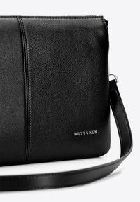 Borsa a tracolla in pelle nera con superficie testurizzata, cuciture a contrasto e dettaglio logo in argento. Include una tracolla regolabile.