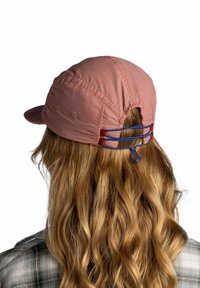 Gorra rosa hecha de tela ligera, con un visor curvado, respaldo ajustable y cordones de acento azul. Textura suave y ajuste relajado.